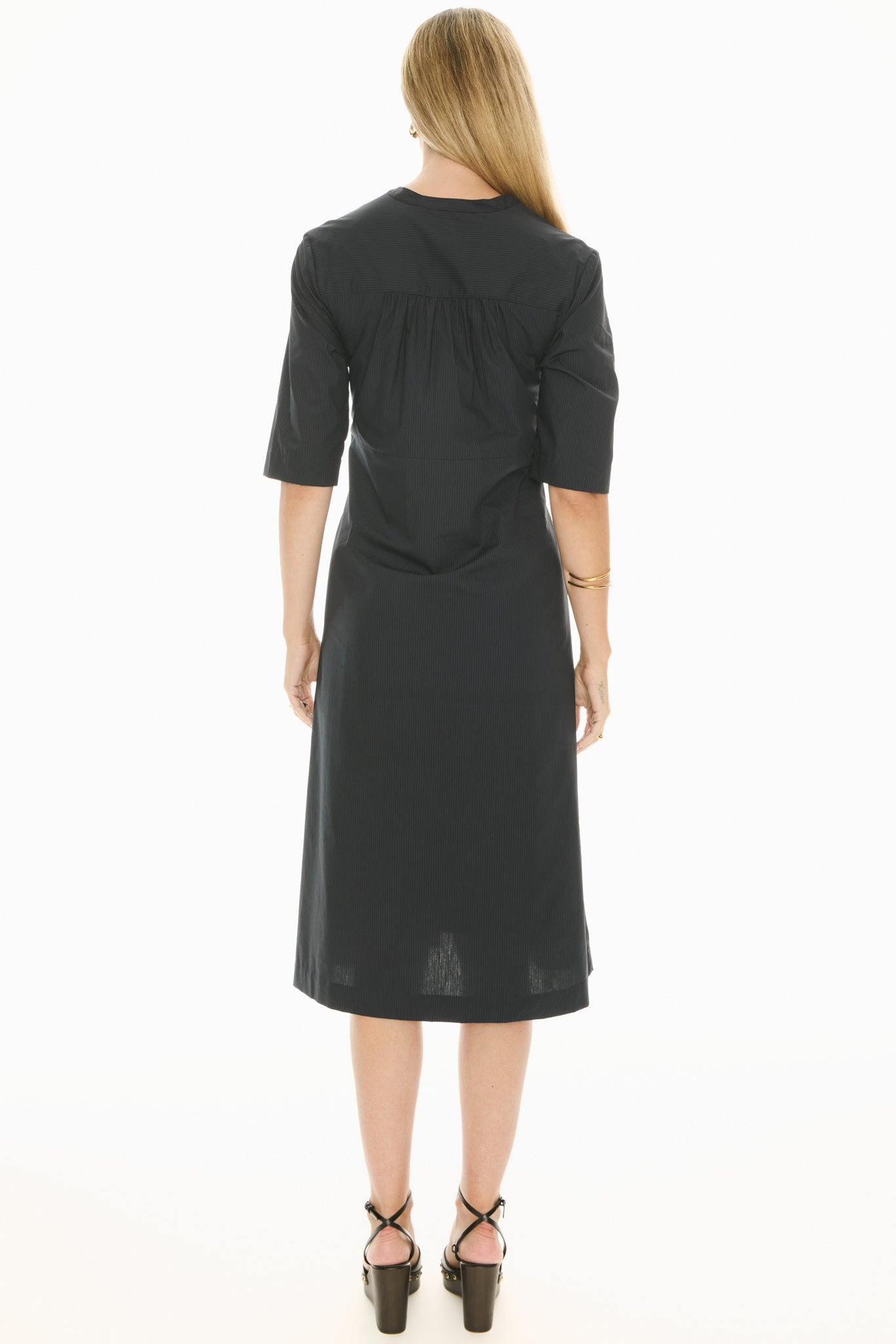 Woman wearing a ink blue short sleeve midi dress with a tie waist on a white background