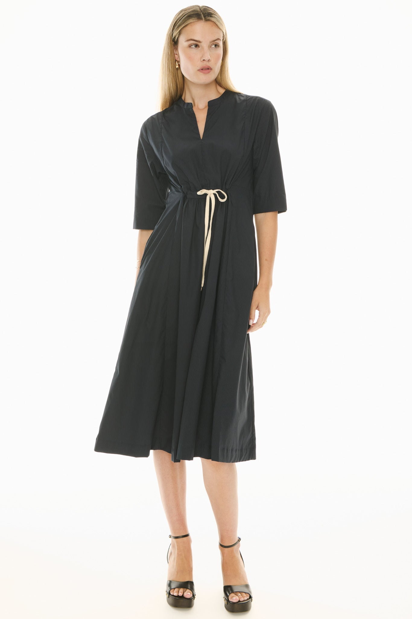 Woman wearing a ink blue short sleeve midi dress with a tie waist on a white background