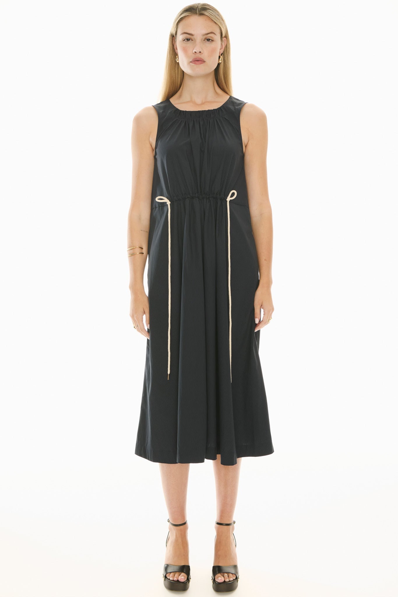 Model wearing a ink blue sleeveless midi dress with gathered waist on a white background