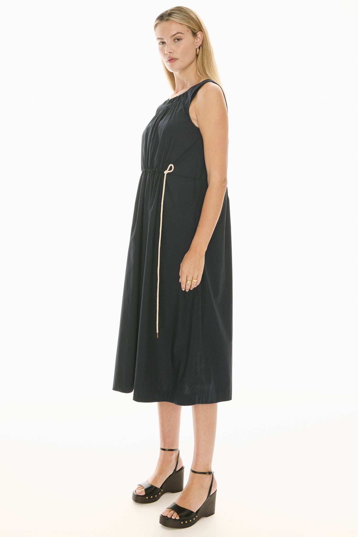 Model wearing a ink blue sleeveless midi dress with gathered waist on a white background