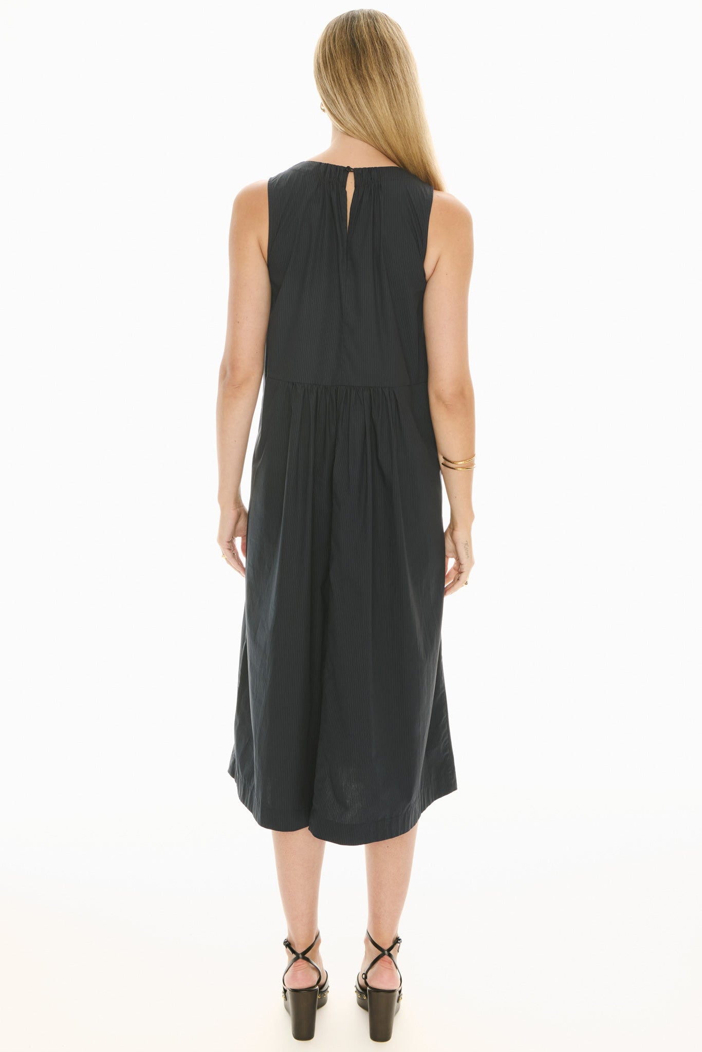 Model wearing a ink blue sleeveless midi dress with gathered waist on a white background