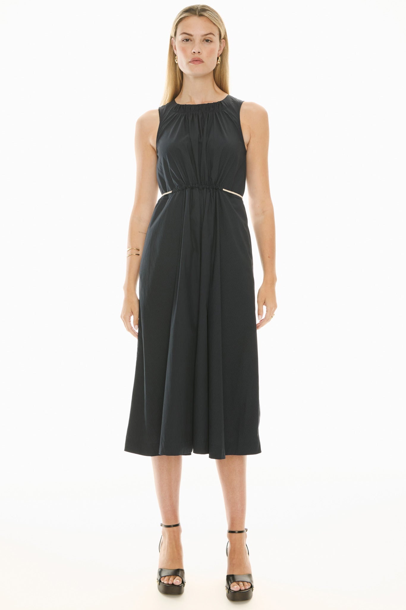 Model wearing a ink blue sleeveless midi dress with gathered waist on a white background