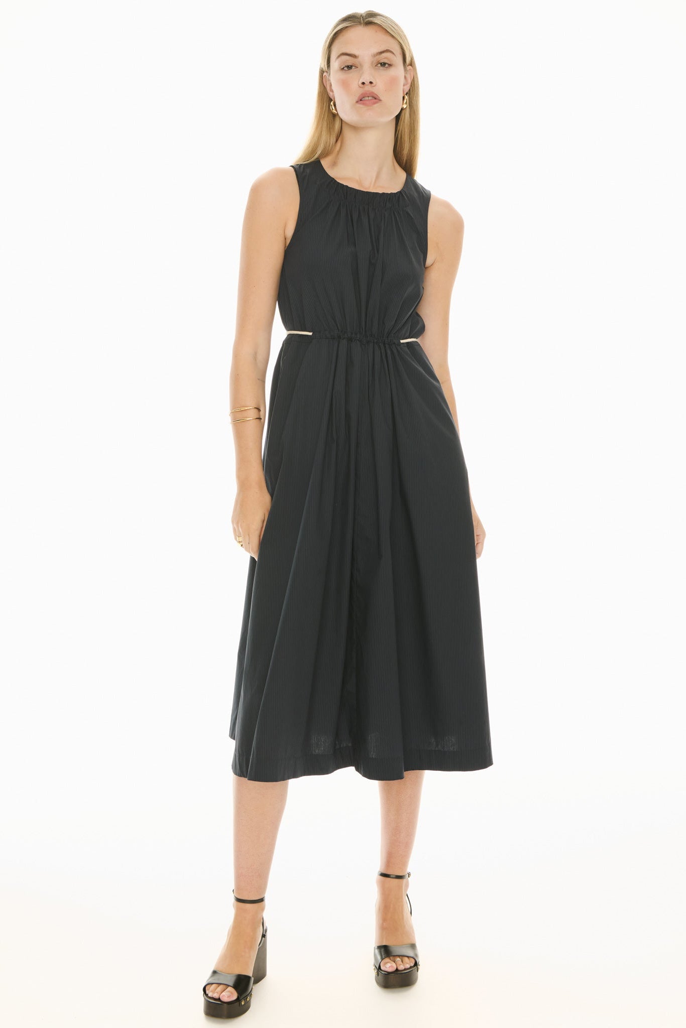 Model wearing a ink blue sleeveless midi dress with gathered waist on a white background