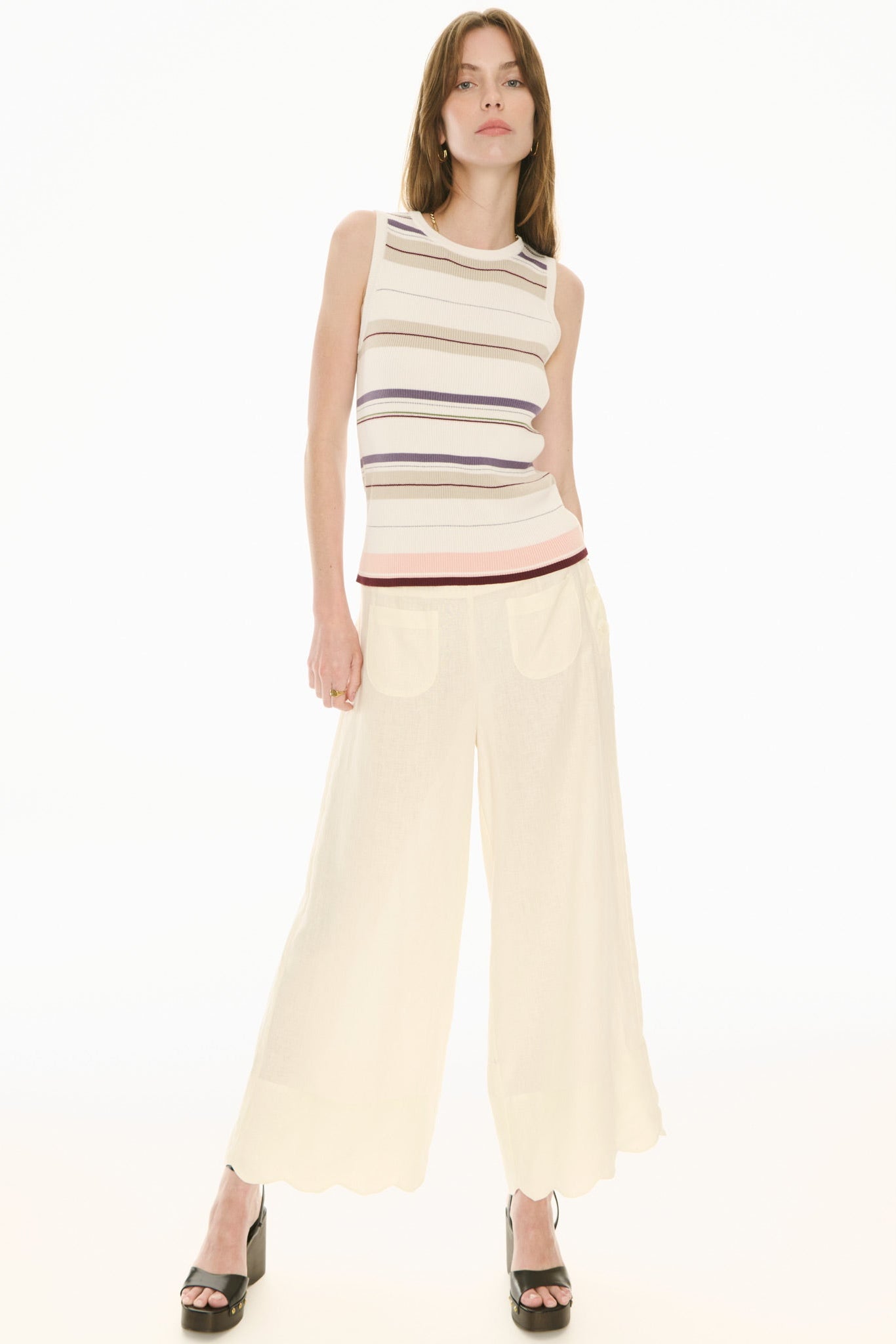 Woman wearing a sleeveless striped top and wide-leg pants on a white background