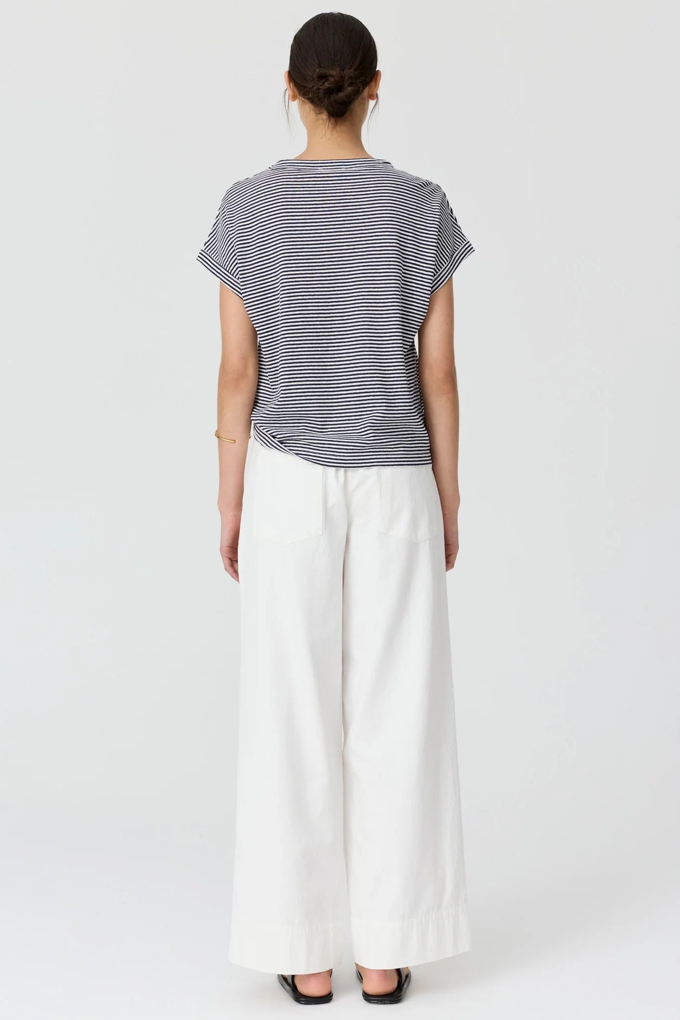Model shown from the back wearing a navy and white stripe short sleeve tee and white wide leg pants and sandals. 