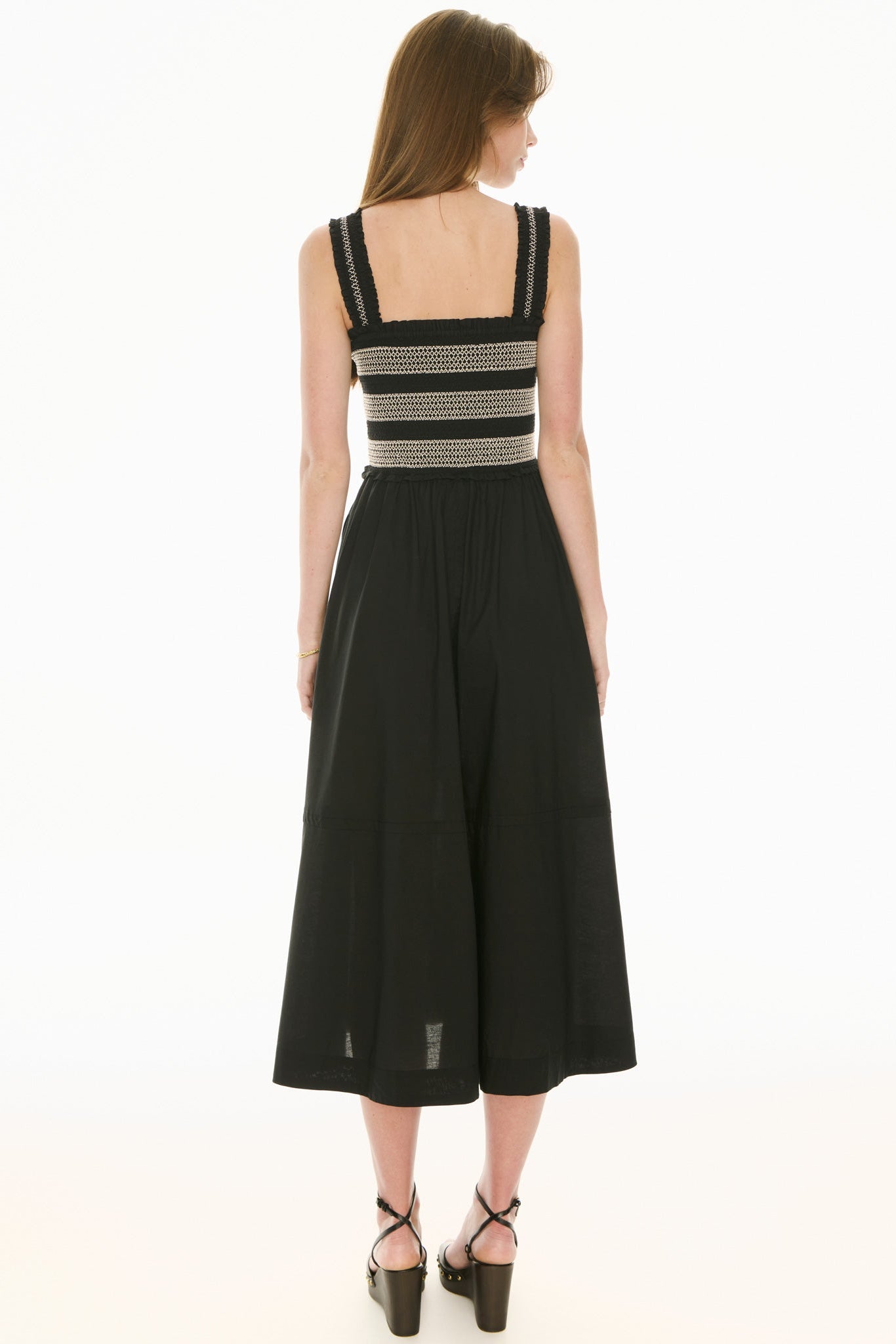 Model wearing black and white sundress with smoked bodice on a white background.  