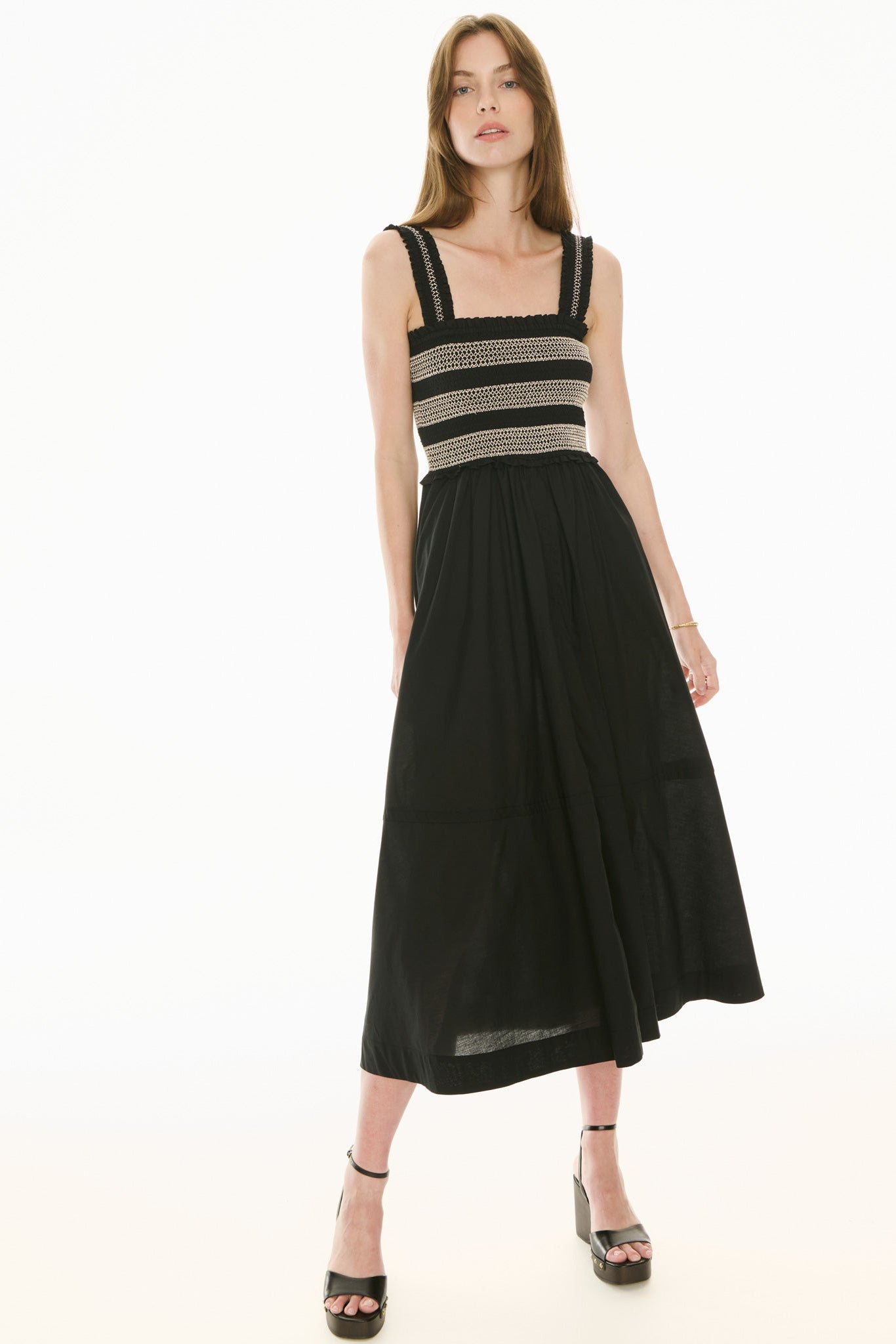 Model wearing black and white sundress with smoked bodice on a white background.  