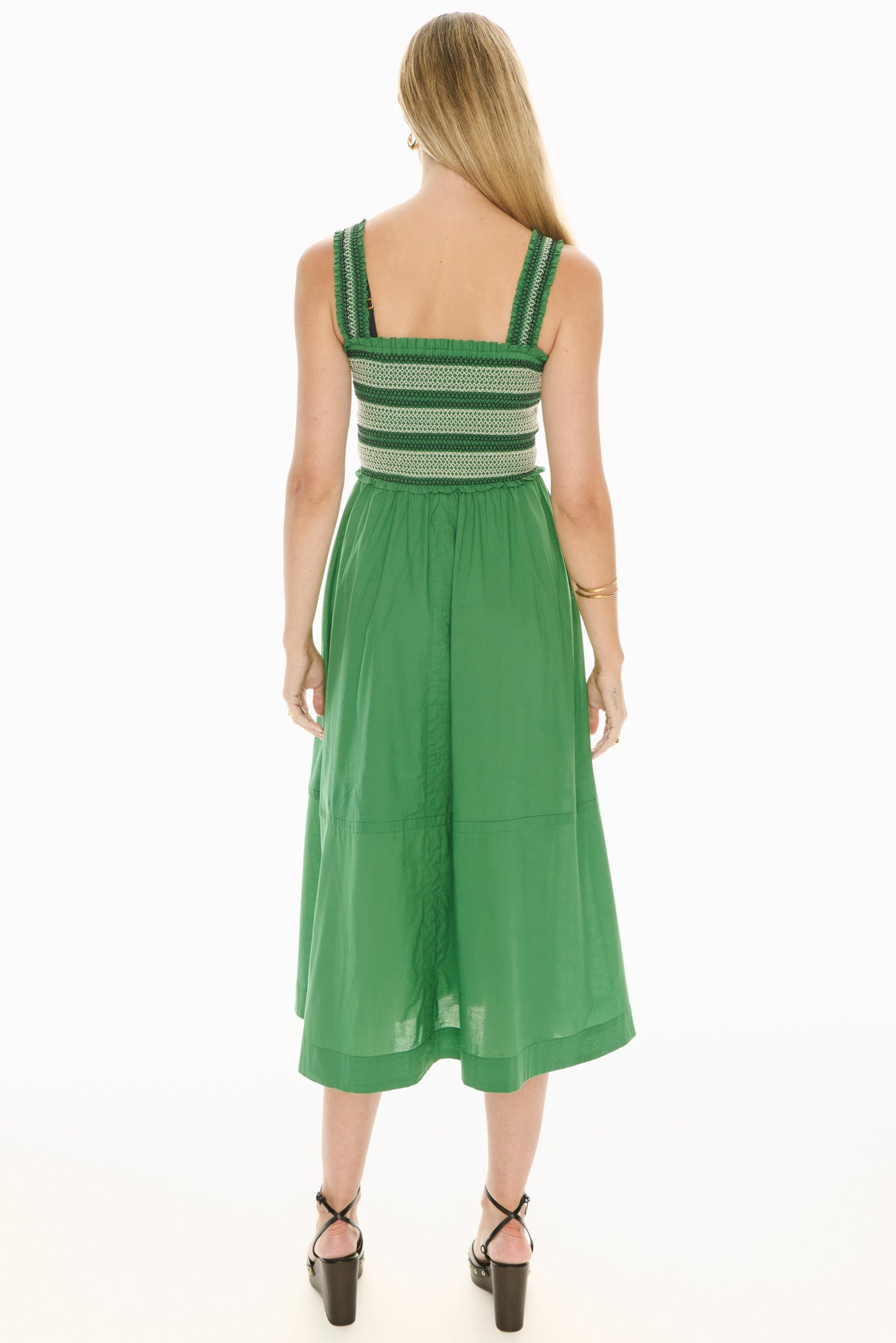 Model wearing a green and white sundress with smoked bodice on a white background. 