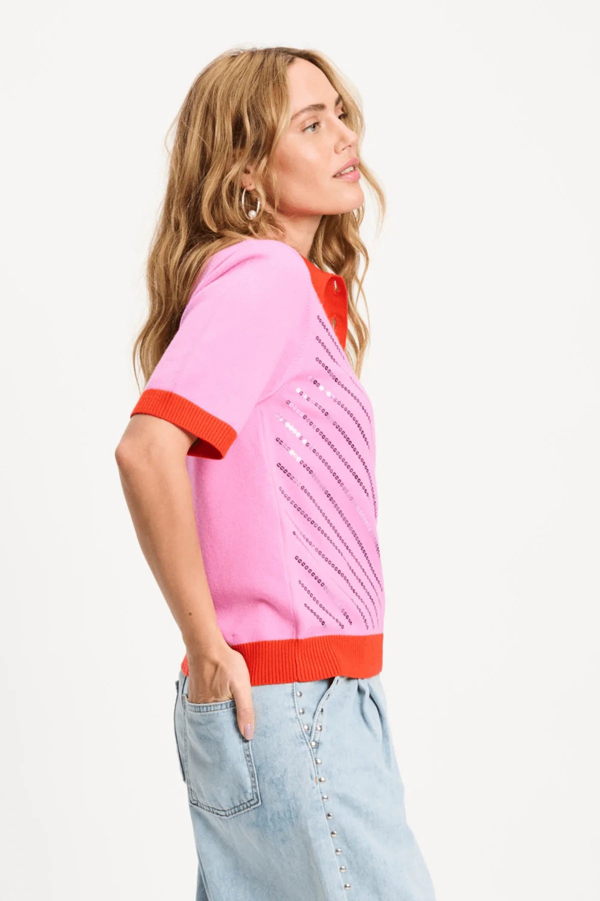 Woman wearing a pink sweater with red accents on a white background