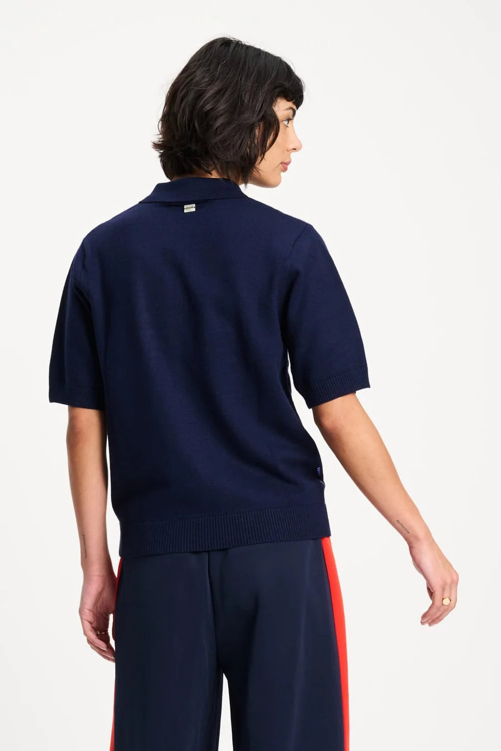 Person wearing a navy blue sweater and pants with a red stripe on a white background