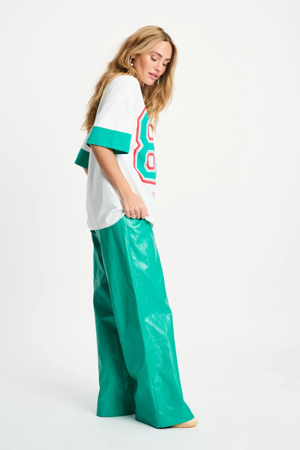 Woman wearing a white and green outfit with a colourful design on a white background