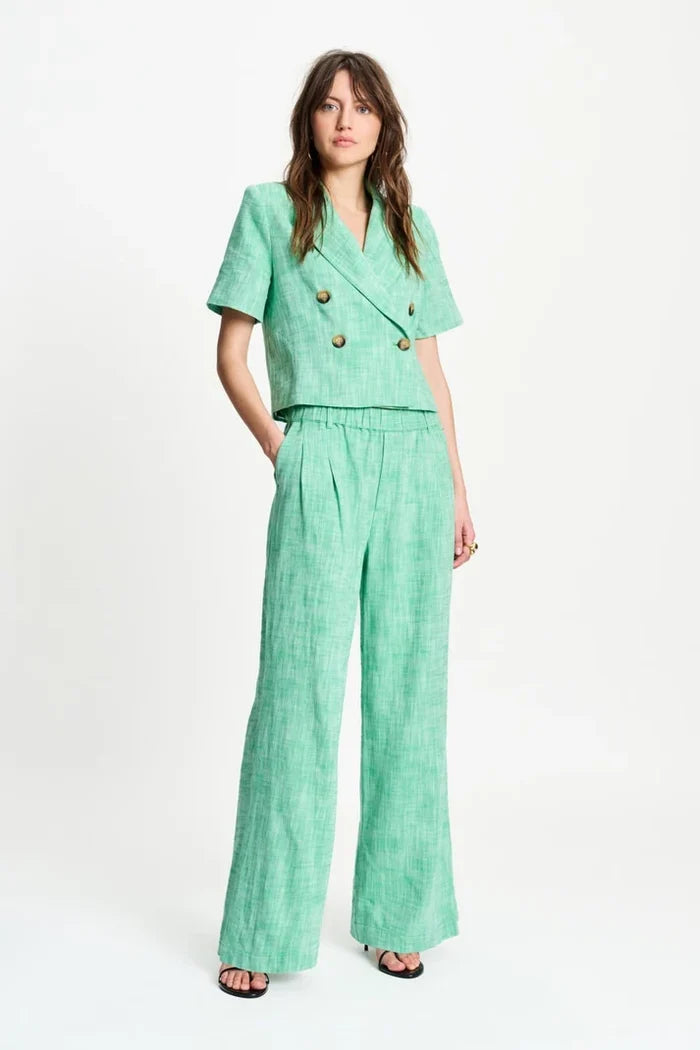 Woman wearing a green short sleeve cropped blazer and matching pants on  a white background