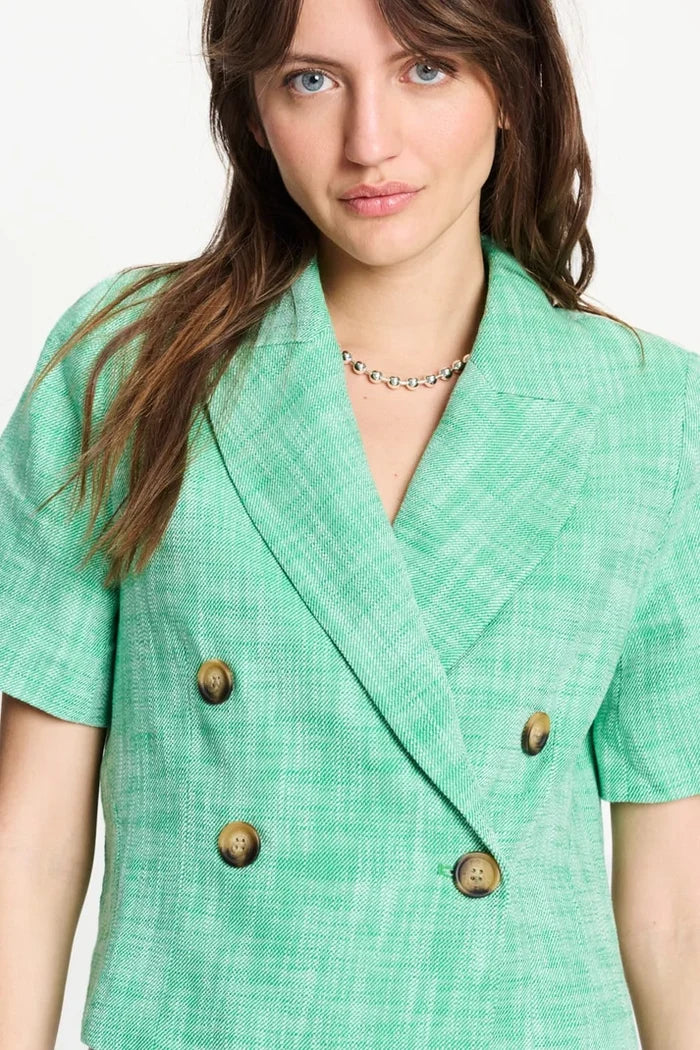 Woman up close  wearing a green short sleeve cropped blazer with silver necklace on  a white background