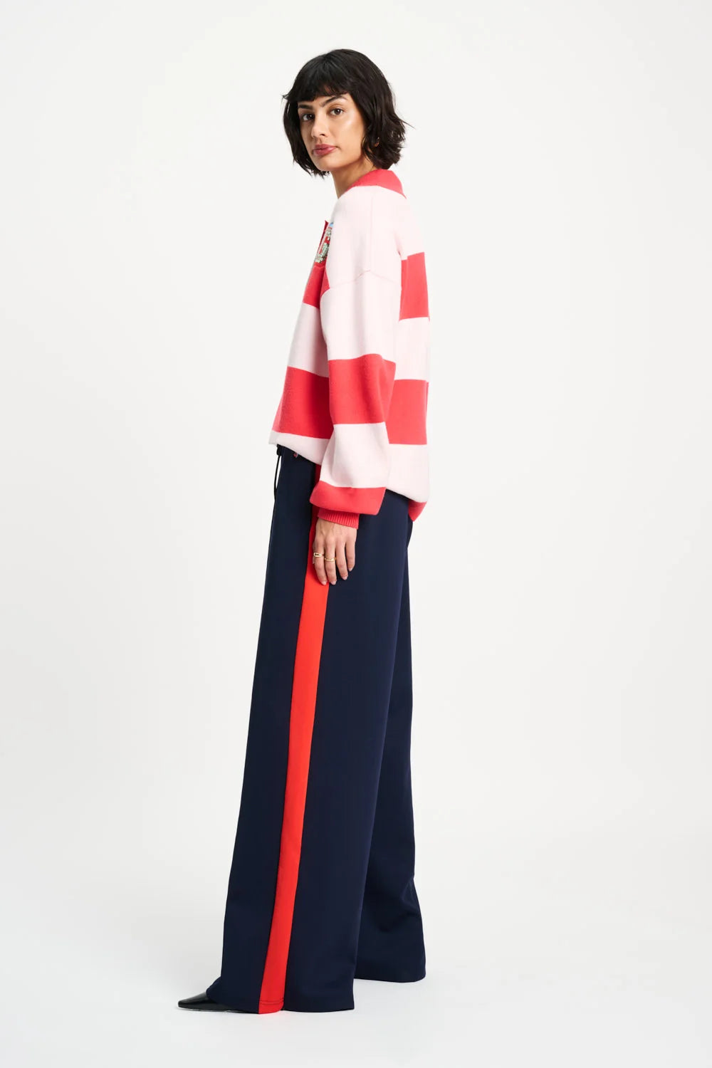 Person wearing a striped sweater and wide-leg pants with a red stripe on a white background