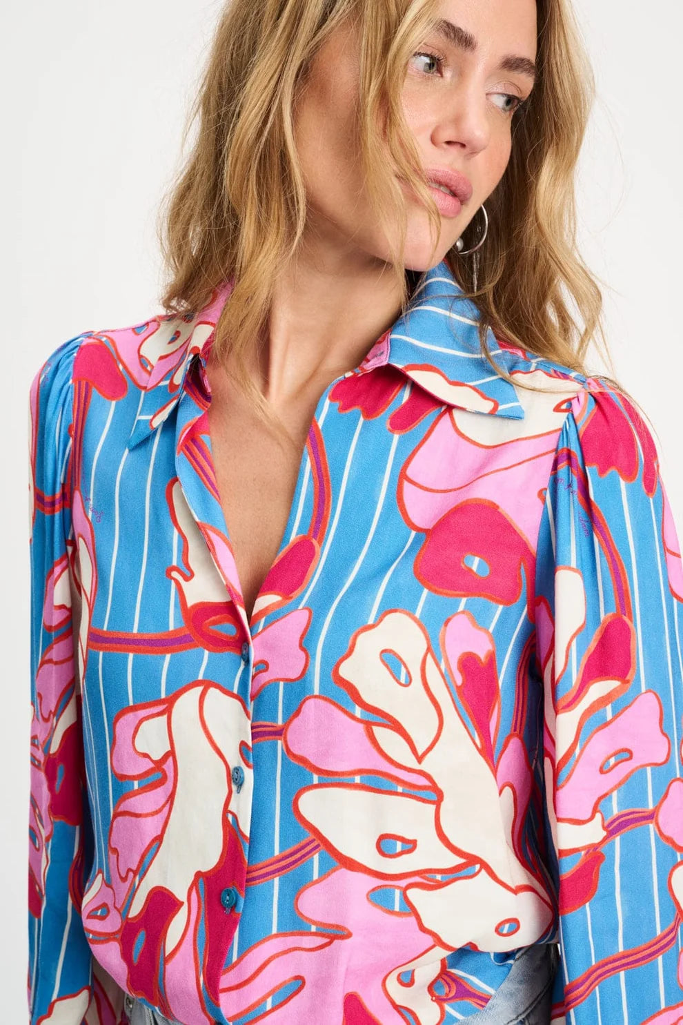 Woman wearing a colourful floral blouse up close with a white background