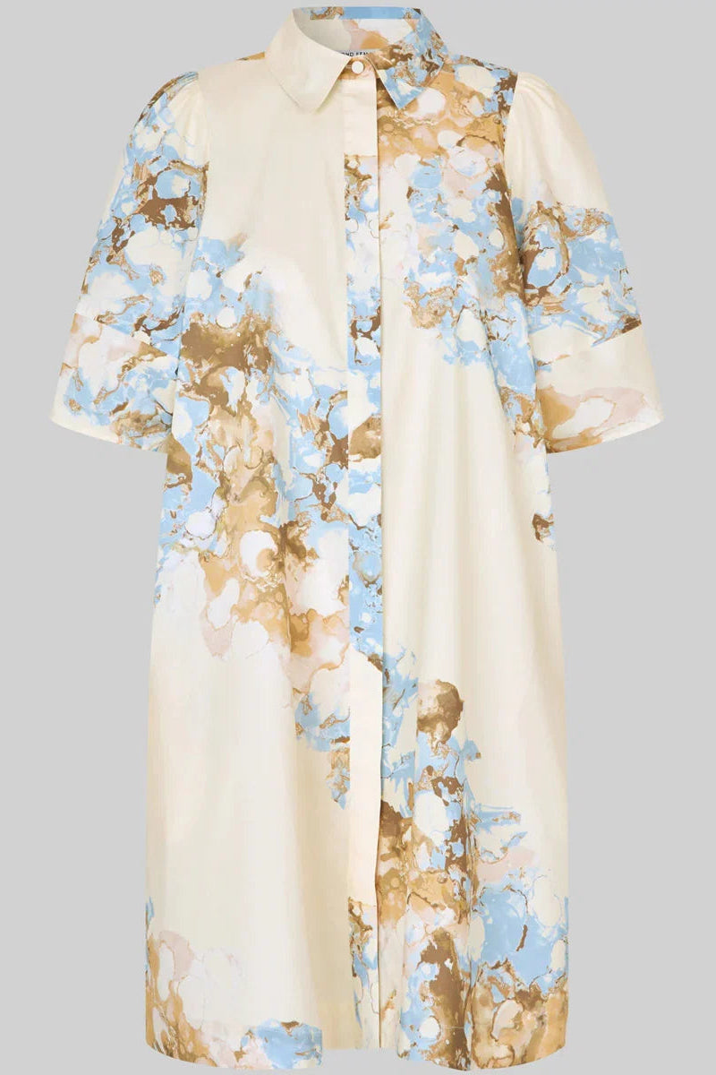 A cream-colored short-sleeve button-up shirt dress with a watercolor-style floral print in light blue and brown, shown against a solid gray background.