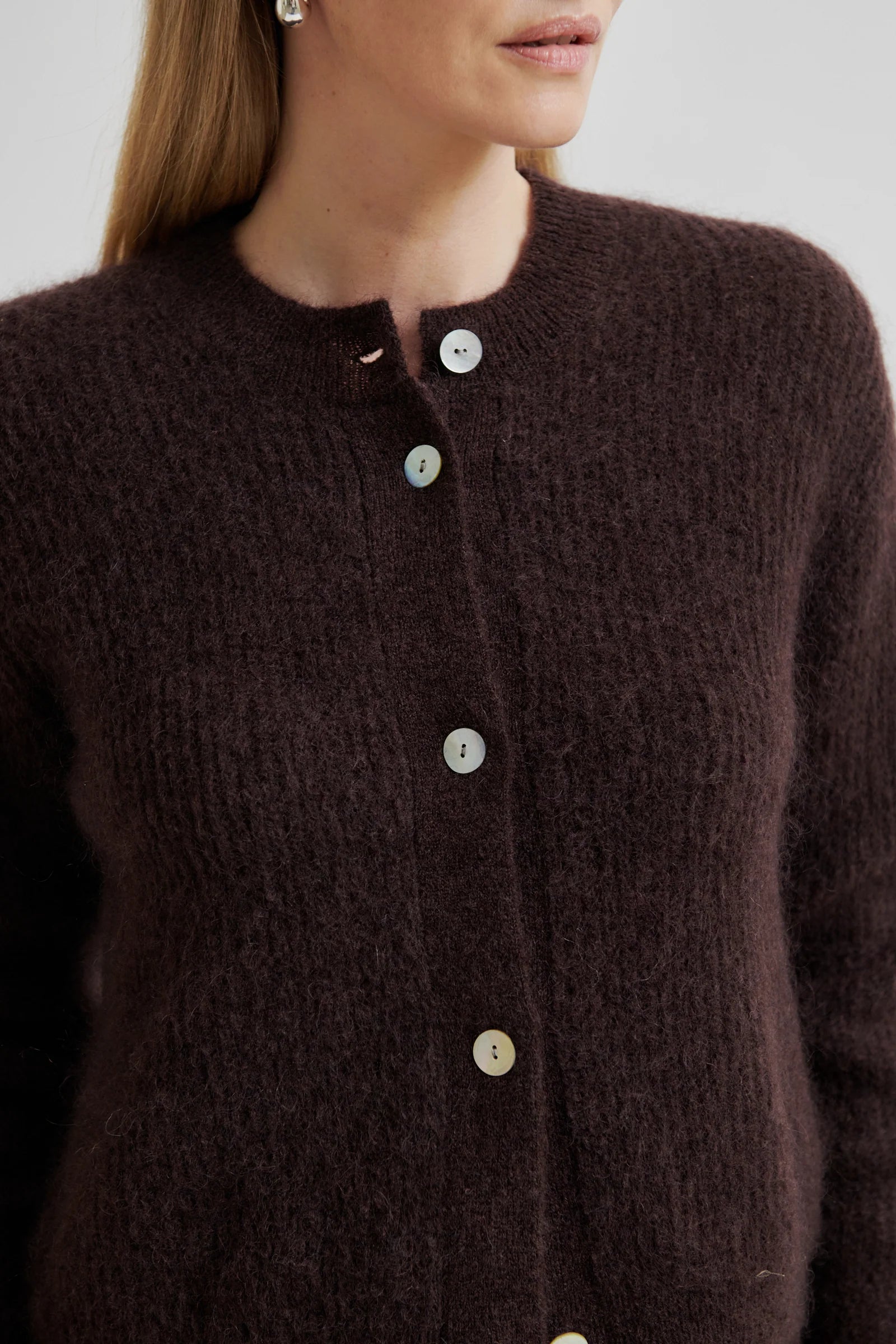 Close-up of a brown textured cardigan with button details.