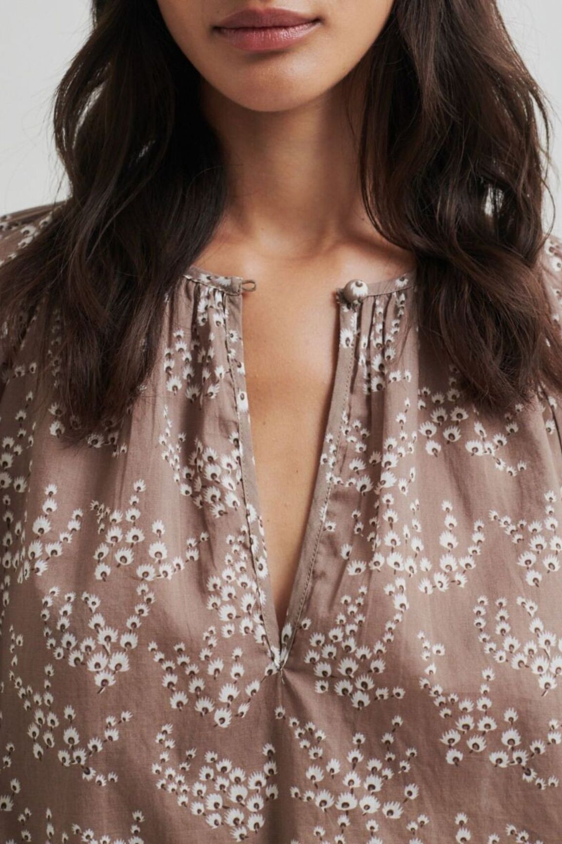 Close-up of a person wearing a patterned blouse with a neutral background