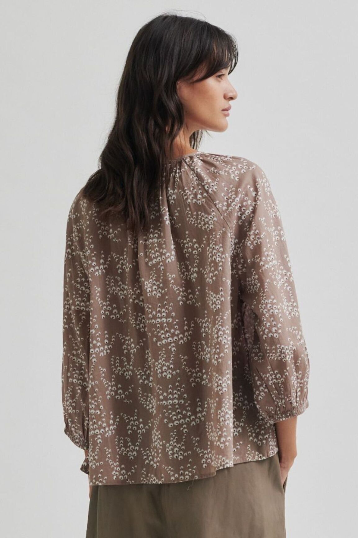 Woman wearing a patterned blouse against a plain background