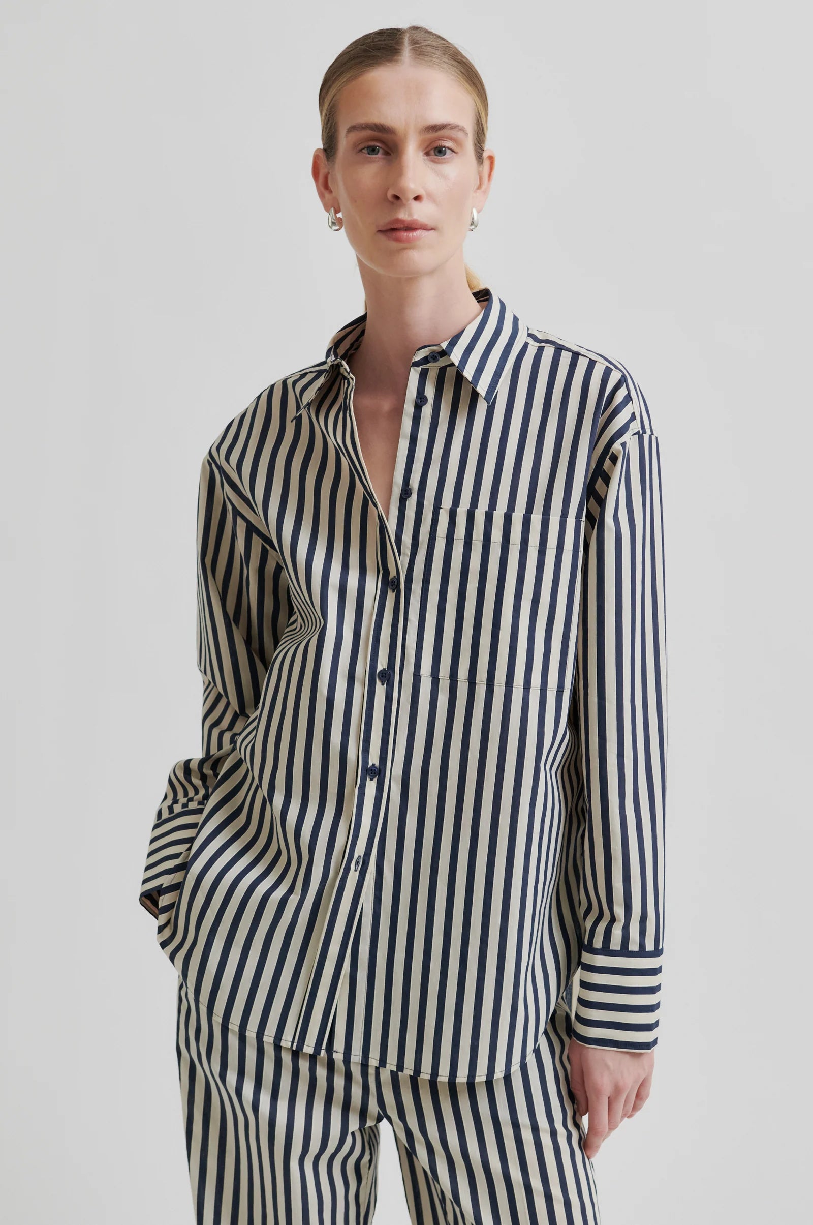 Person wearing navy and beige striped shirt and pants on a plain background