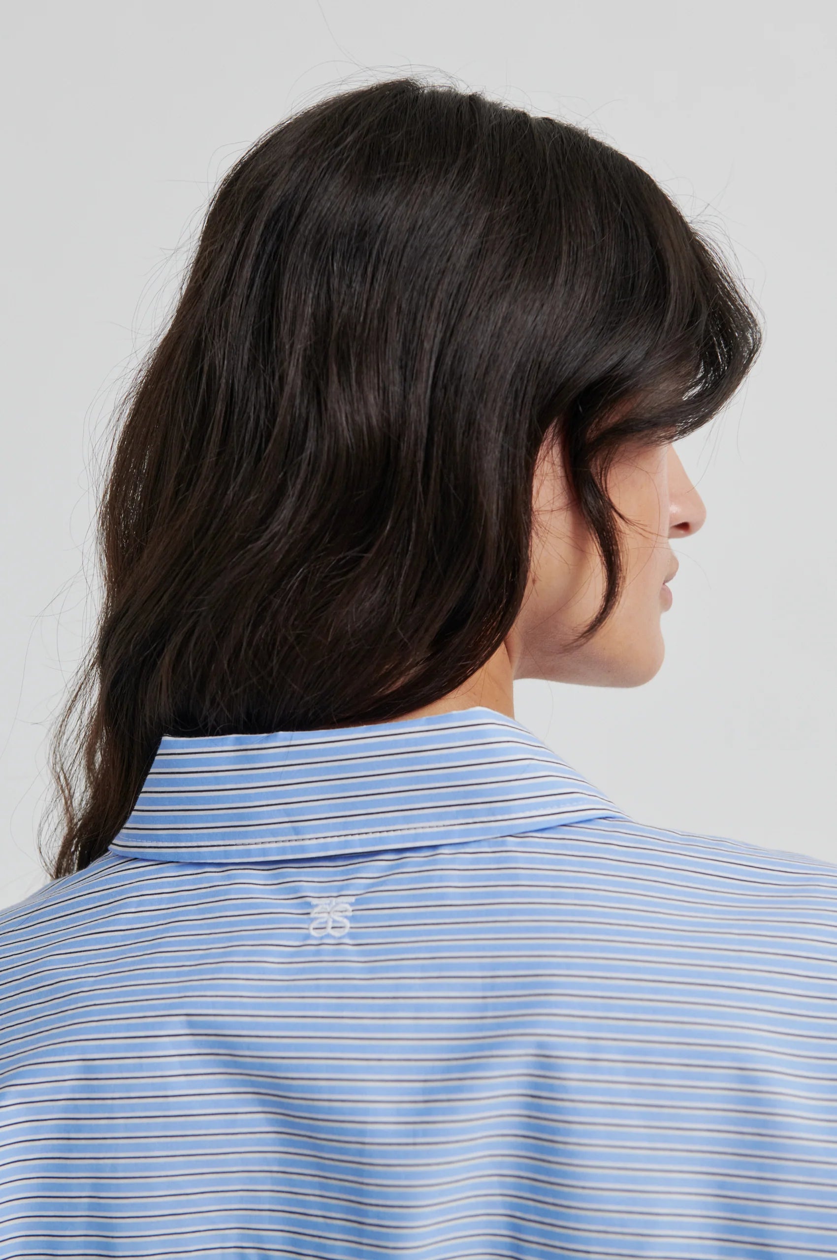 Person wearing a blue striped shirt with a white background