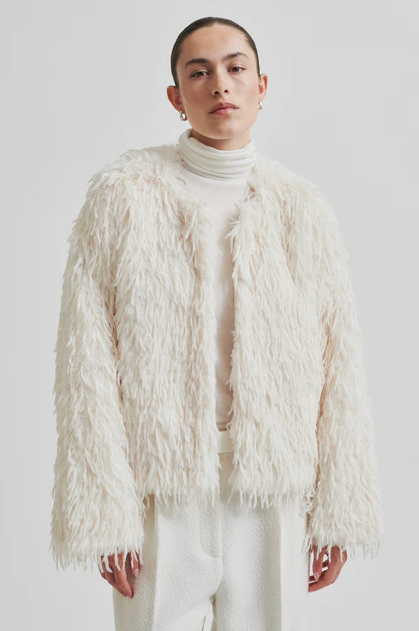 Model wearing Shaggy cream jacket with long sleeve cropped. Paired with cream turtle neck top and cream pants. 
