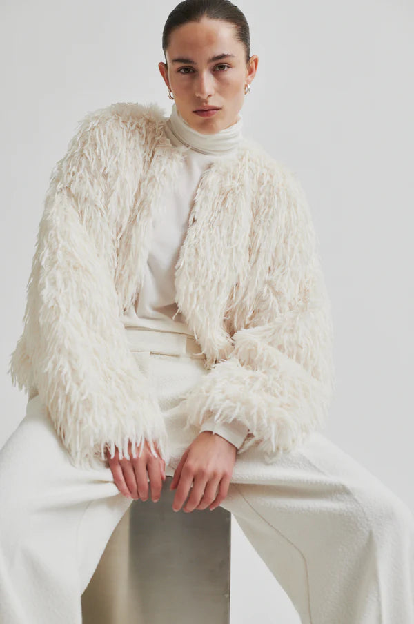 Model wearing Shaggy cream jacket with long sleeve cropped. Paired with cream turtle neck top and cream pants. 