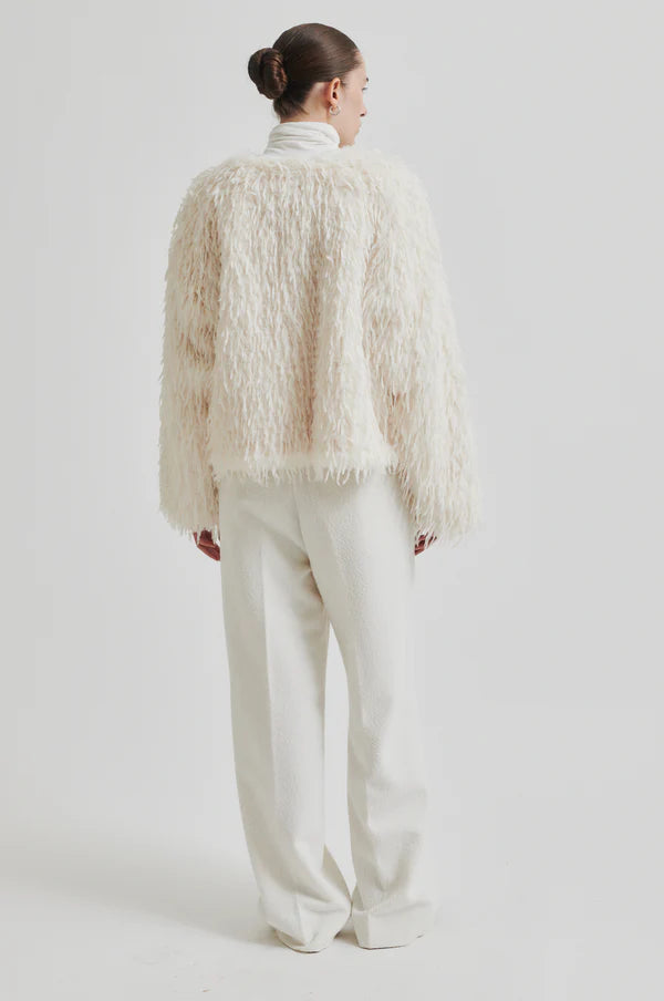 Model wearing Shaggy cream jacket with long sleeve cropped. Paired with cream turtle neck top and cream pants. 