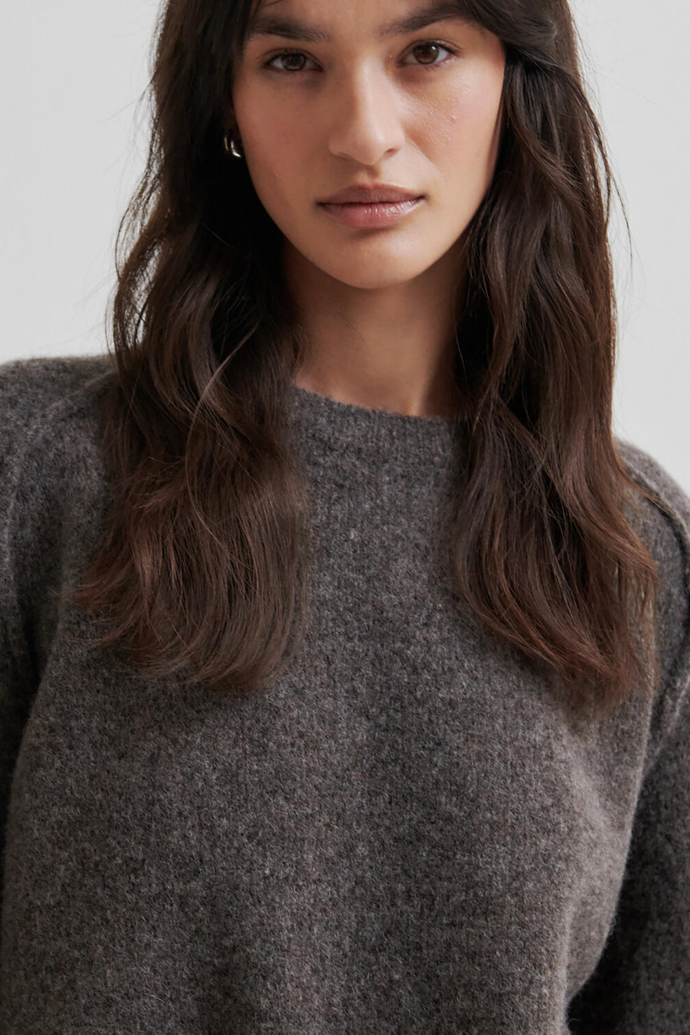 Woman wearing a brown sweater on a light grey background