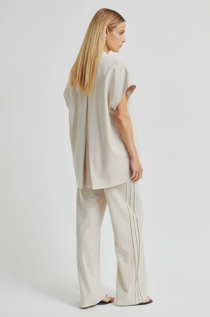 Woman wearing a beige outfit with wide-leg pants on a white background