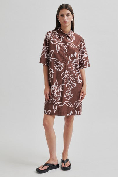 Woman wearing a brown floral tunic dress with collar on a white background