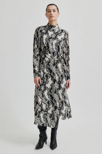 Long sleeve dress with a round, high neckline with keyhole opening at the back with button fastening. Black and white floral print. 