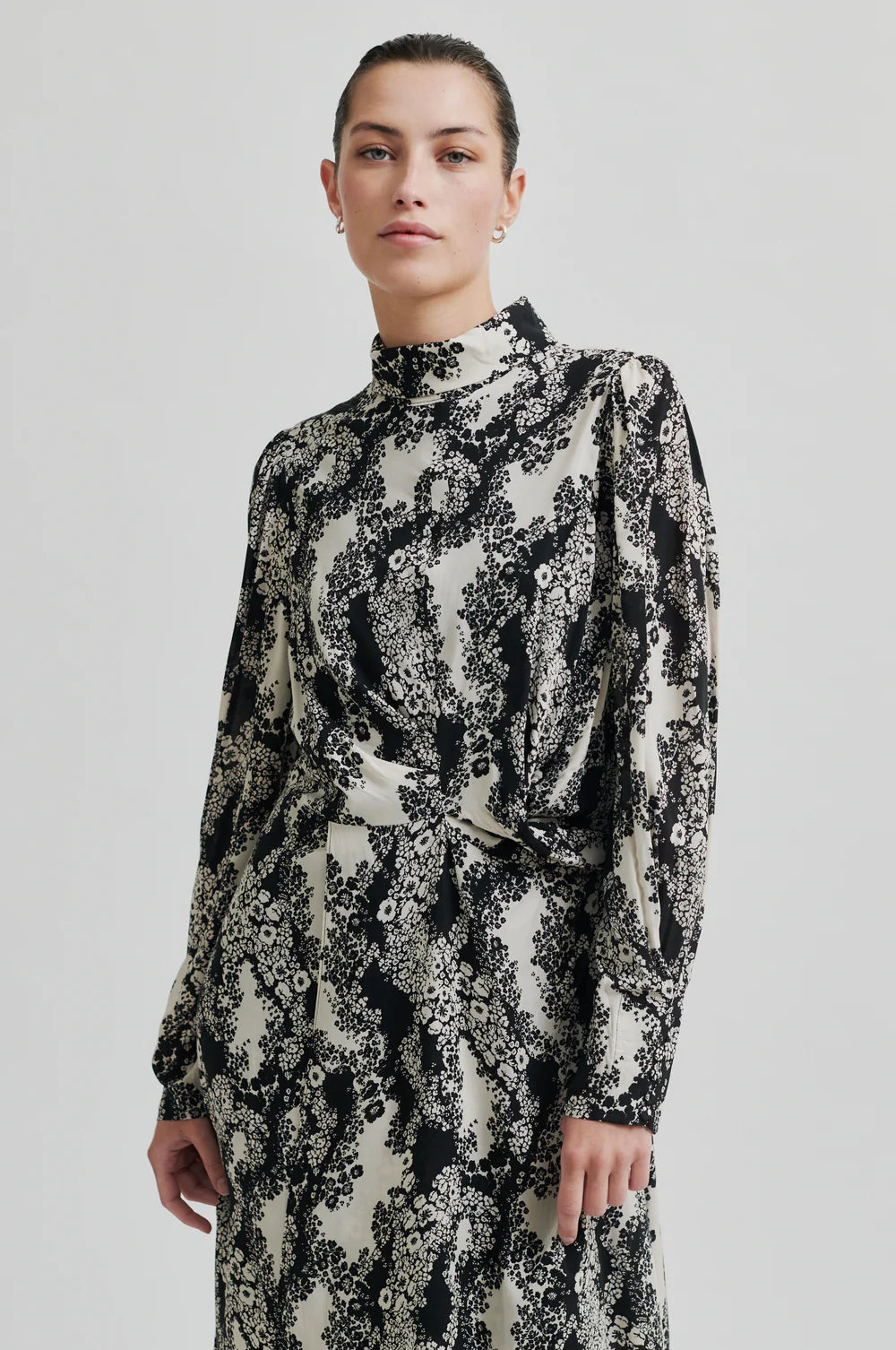Long sleeve dress with a round, high neckline with keyhole opening at the back with button fastening. Black and white floral print. 
