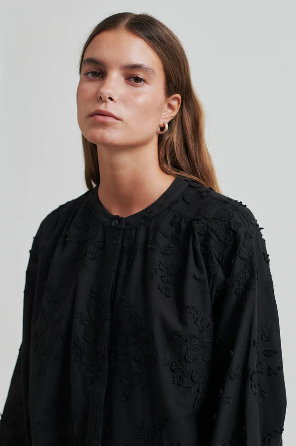 Model wearing a black oversized shirt with embroidery close up