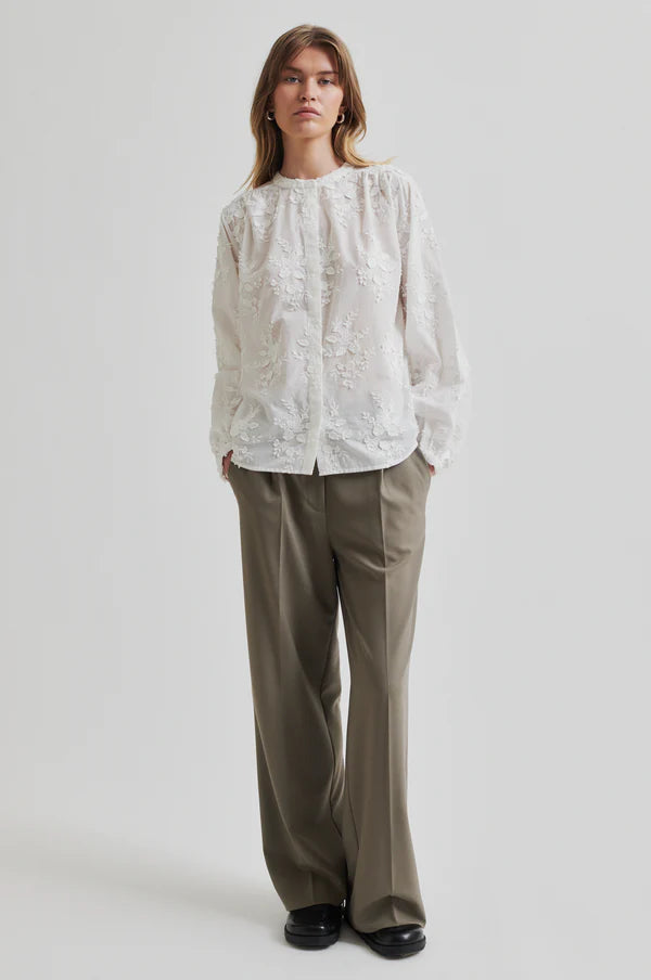 embroidered white shirt with long sleeve paired with neutral wide leg pants. 