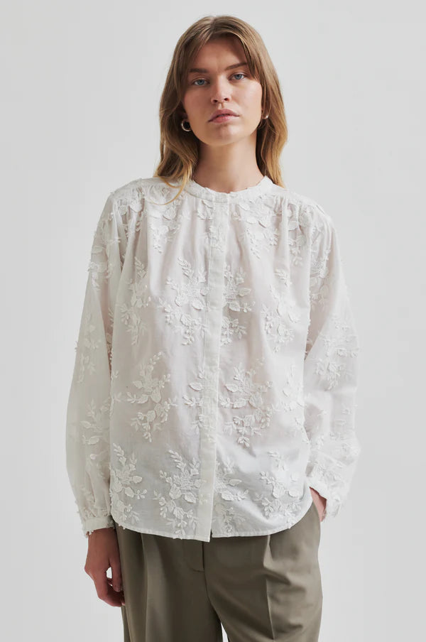 embroidered white shirt with long sleeve paired with neutral wide leg pants. 