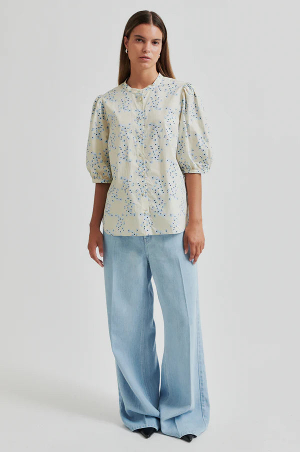 Model wearing a blue floral print blouse on a cream base with puffed sleeves paired with soft blue wide leg pants. 