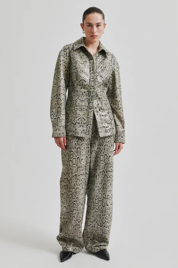 Model wearing mid rise wide leg leather pants with snake skin pattern and matching jacket. 