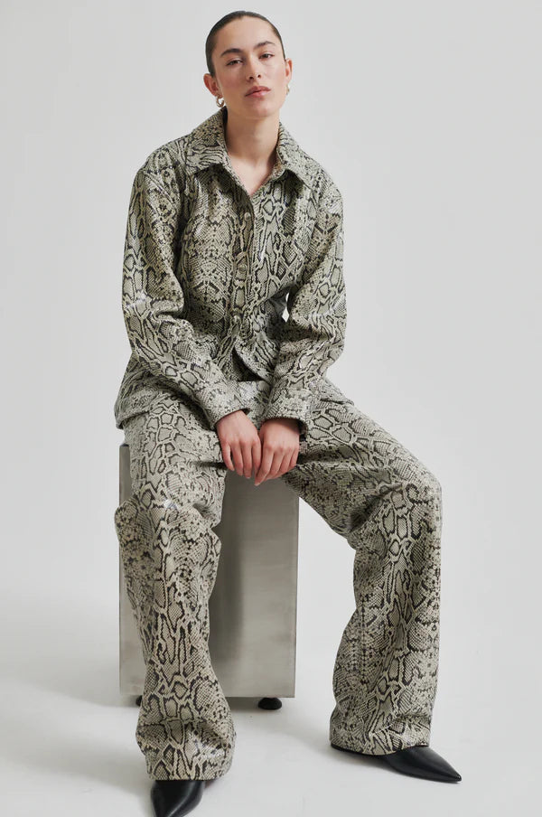 Model wearing mid rise wide leg leather pants with snake skin pattern and matching jacket. 