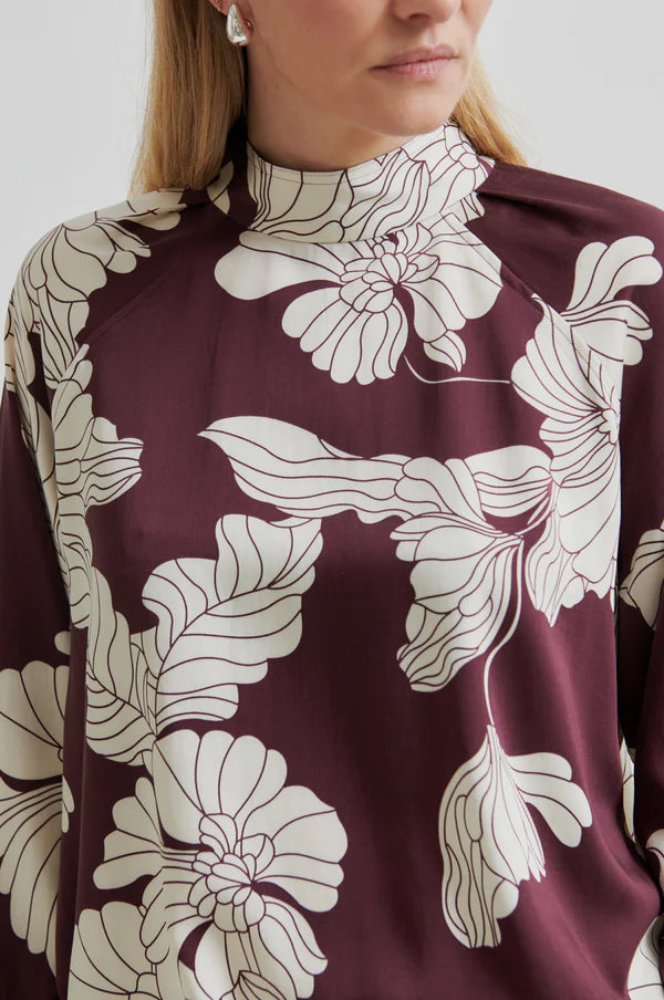 Close-up of a person wearing a burgundy top with white floral patterns.