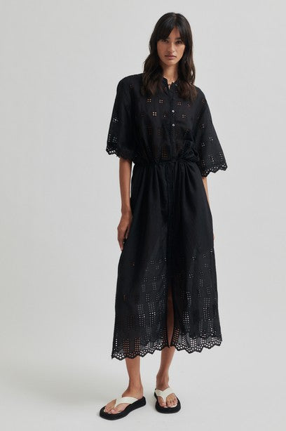 Woman wearing a black short sleeve midi dress with a white background