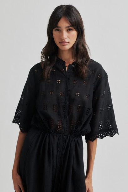 Woman wearing a black short sleeve midi dress with a white background