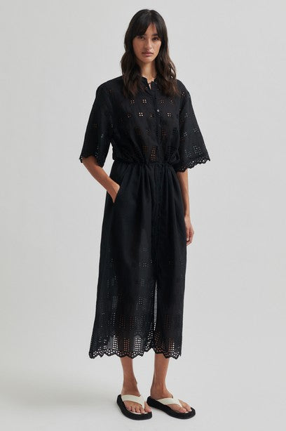 Woman wearing a black short sleeve midi dress with a white background