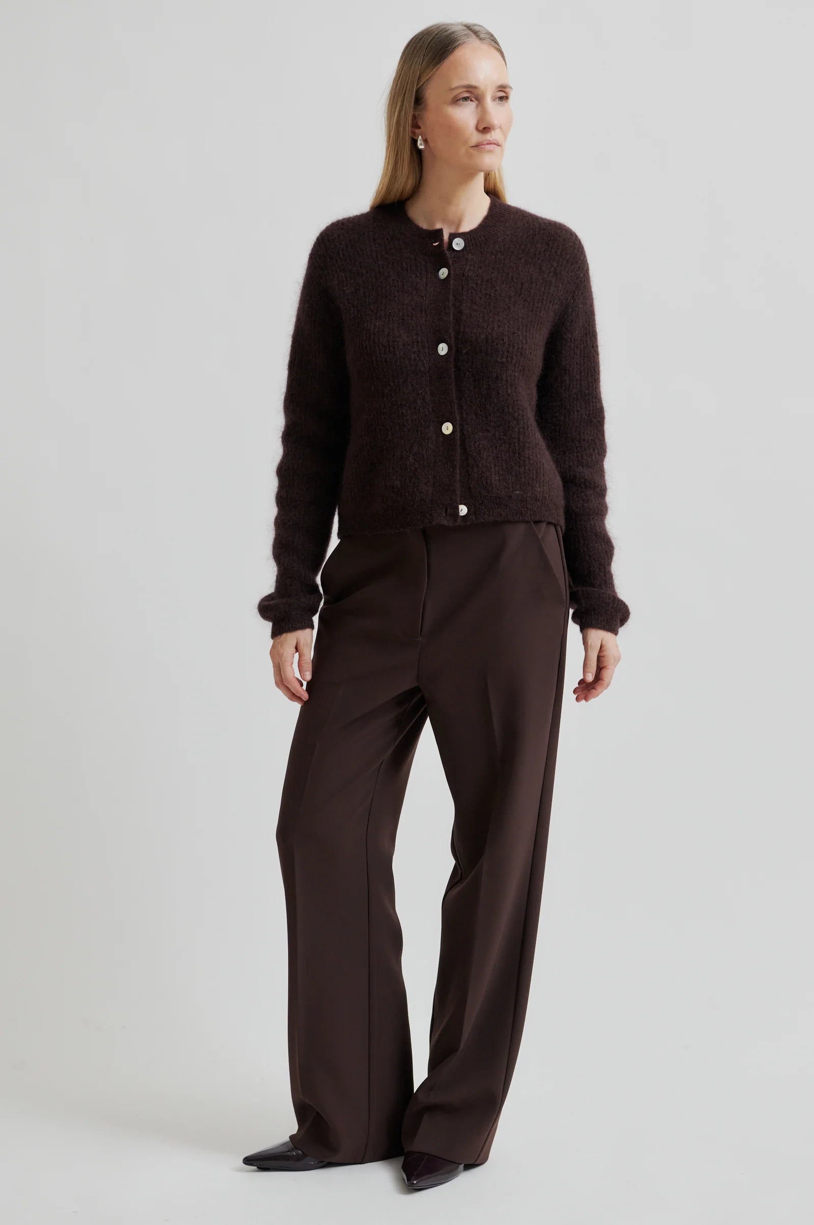 Woman wearing a brown cardigan and pants on a white background
