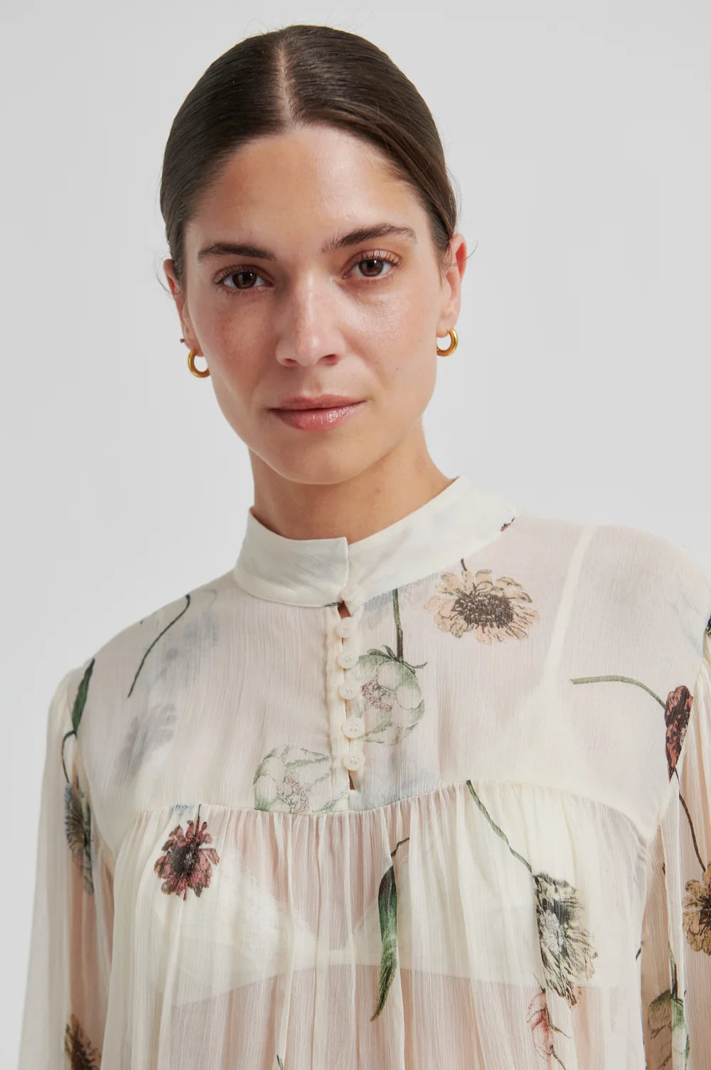 Close-up of model a floral-patterned blouse with a neutral background