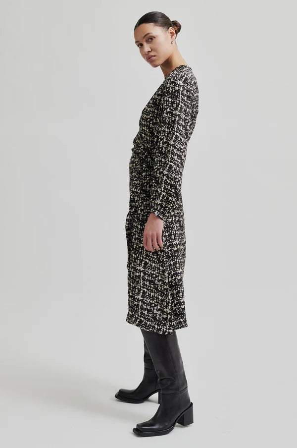 Side view of Monochrome long sleeve dress with crossover front that ties to one side.