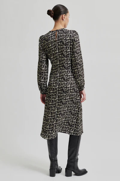 Back View of monochrome long sleeve dress with crossover front that ties to one side.