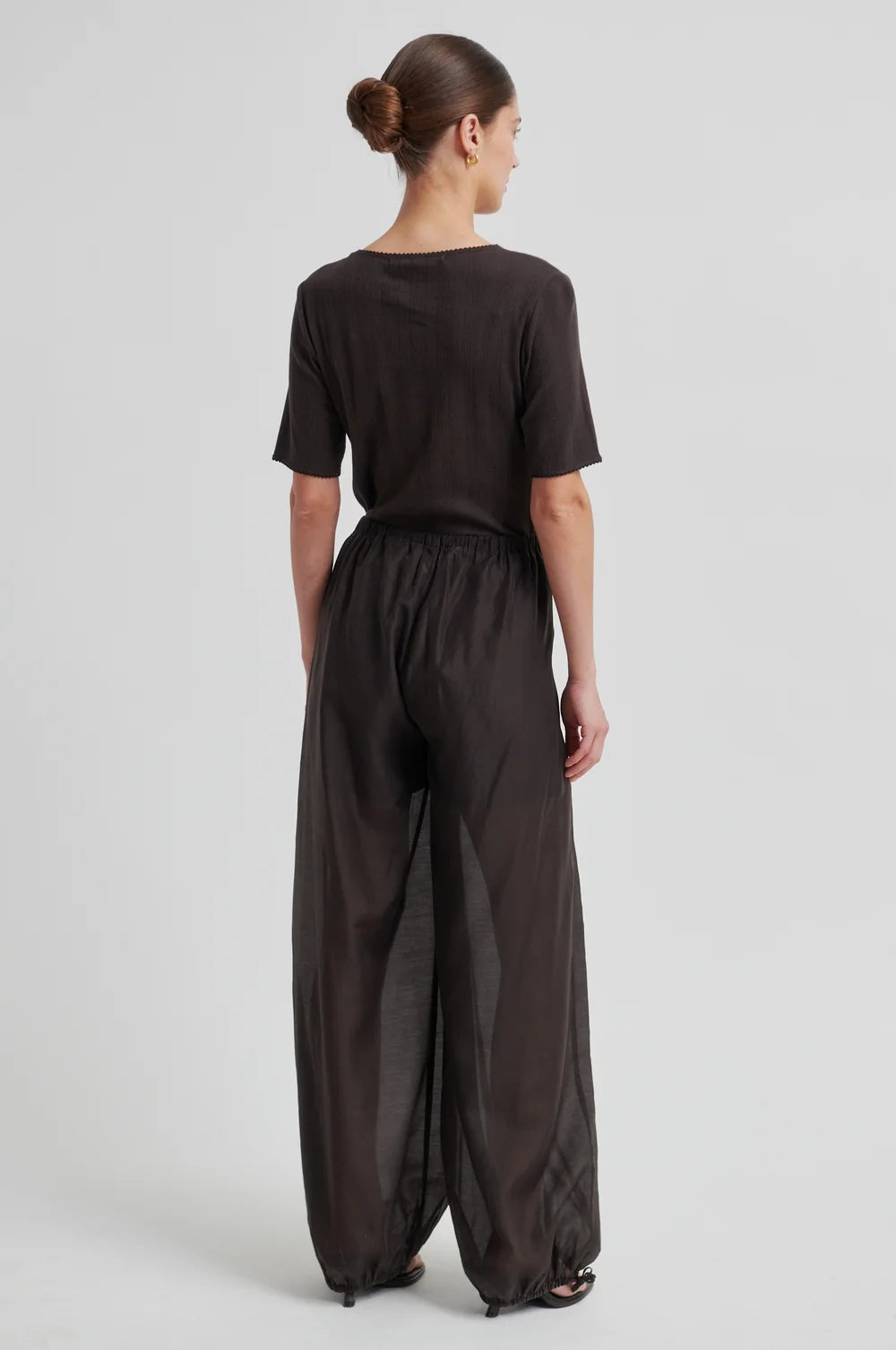 Model shown from back wearing chocolate brown wide-leg pants  that taper and a matching top on a white background