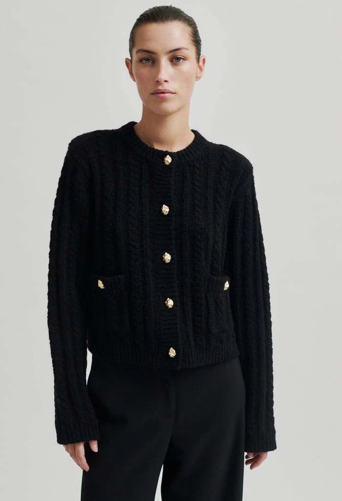 Black mock neck cardigan with gold button detail down front and on two front pockets at hip height. 
