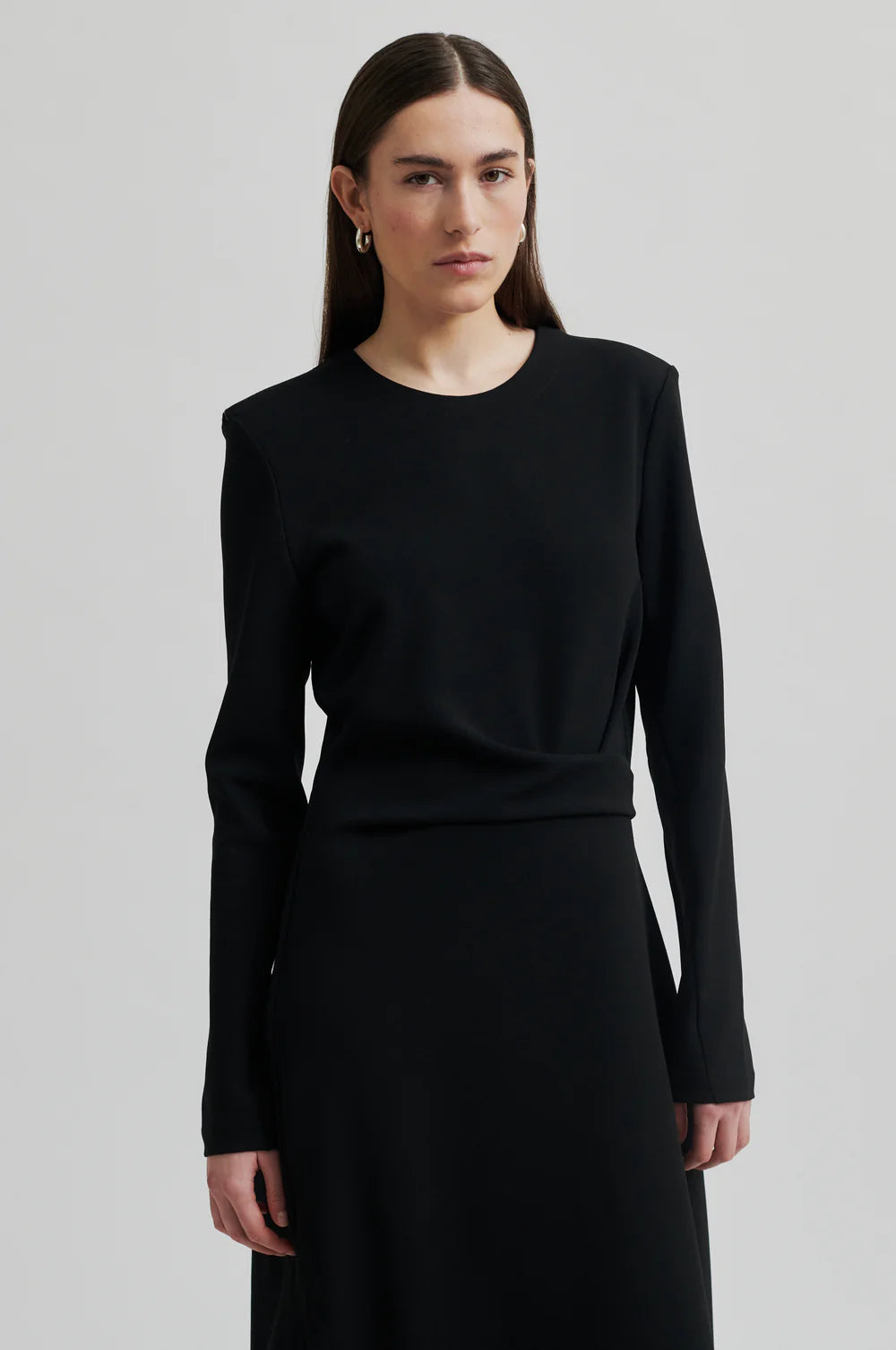 Black long sleeve dress with pleated details at one side that create a flattering draped effect. Front slit. 